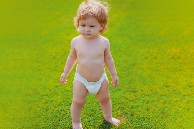 Beautiful baby walking in the park in diaper pants. Healthy child.