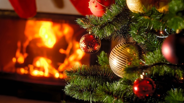 Beautiful background of burning fireplace and decorated Christmas tree with baubles and garlands