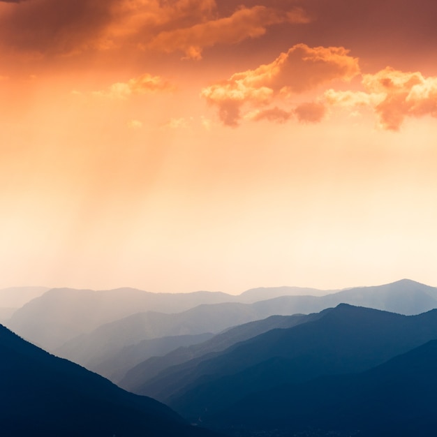 Beautiful background with cascade of blue mountains and red sunset sky with clouds