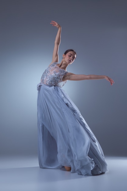 The beautiful ballerina dancing in long lilac dress on lilac