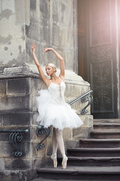 Beautiful ballerina dancing near an old building