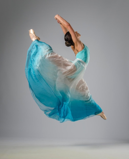Photo beautiful ballerina dancing with blue and white clothes. she danced on ballet pointe shoes.