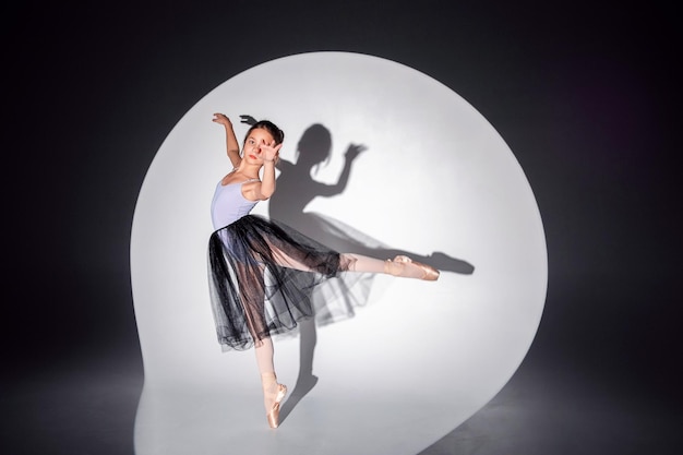 Фото Красивая балерина танцует на пуантах на фоне циклорамы. соло балета.