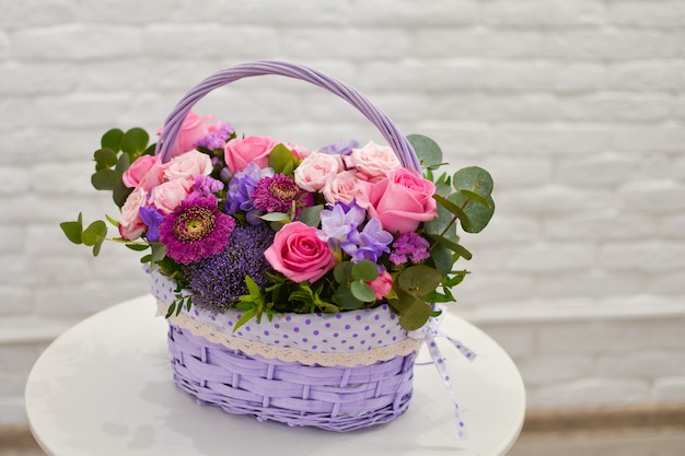 Beautiful basket with fresh flowers on the white table