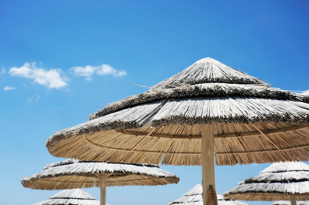 Foto bellissimo resort sulla spiaggia con ombrelloni di paglia bianca su un cielo blu e nuvole bianche vita da spiaggia e concetto di stile di vita torre lapillo salento puglia italia