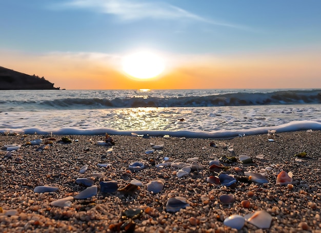 海岸の背景にシーグラスビーチの小石、砂、貝殻でいっぱいの夕日の美しいビーチ