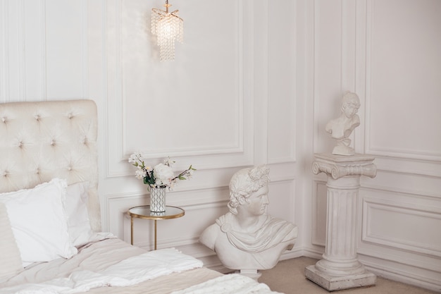 Beautiful bedroom in beige colours with antique sculptures