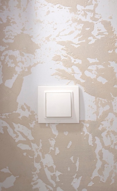 Beautiful beige decorative wall with white plastic switch close up