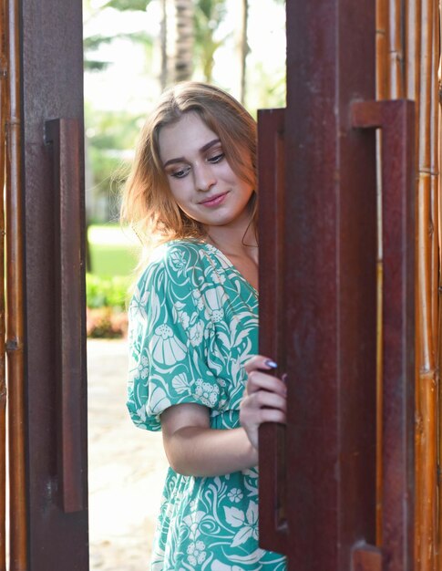 Beautiful Belarus woman in green dress closing the door