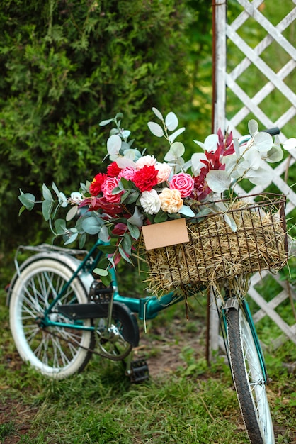 バスケットの花と美しい自転車は、夕暮れ時の公園の大通りに立っています。