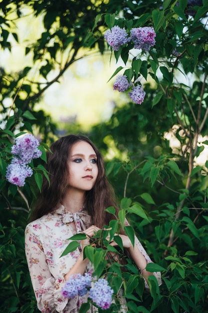 Beautiful big-eyed girl near the lilac tree. 