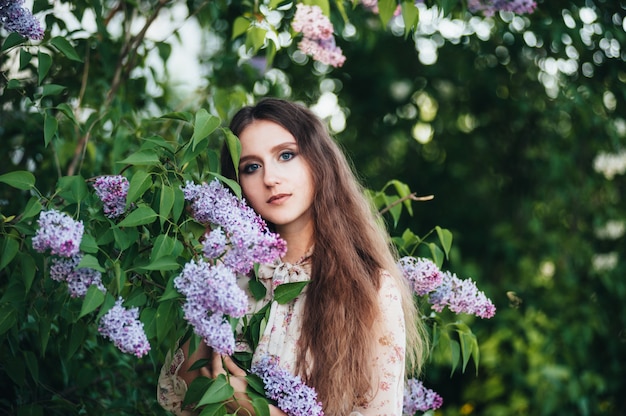 Beautiful big-eyed girl near the lilac tree. 