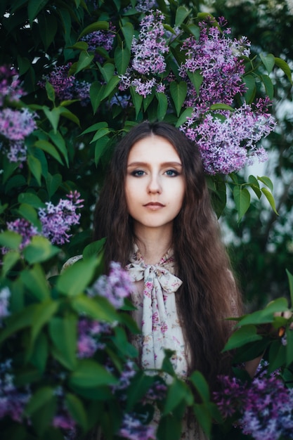 Beautiful big-eyed girl near the lilac tree. 