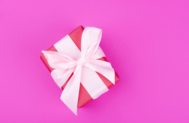 Beautiful big gift box with a bright ribbon on a pink background.