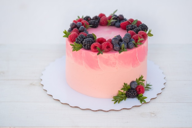 Beautiful birthday cake with blackberries and blueberries on white background