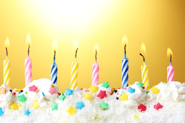 Photo beautiful birthday candles on yellow background