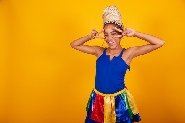 Photo beautiful black brazilian woman dressed in carnival clothes blue and yellow background bun and braids pose for selfie