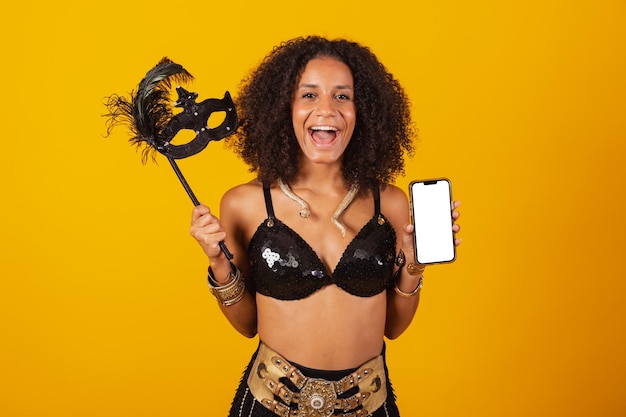 beautiful black Brazilian woman, dressed in carnival clothes, holding smartphone with white screen f