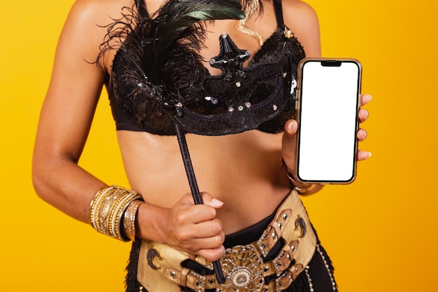 beautiful black Brazilian woman, dressed in carnival clothes, holding smartphone with white screen f