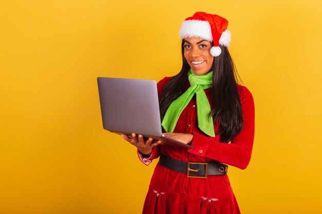 Beautiful black brazilian woman dressed in christmas clothes santa claus holding notebook