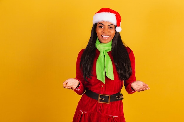 写真 クリスマスの服を着た美しい黒人のブラジル人女性サンタクロースが手で誘う