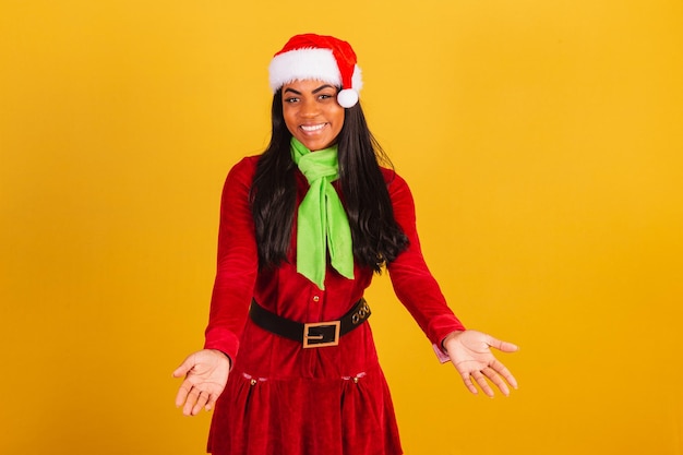 Фото Красивая черная бразильянка в рождественской одежде приветствует санта-клауса с распростертыми объятиями