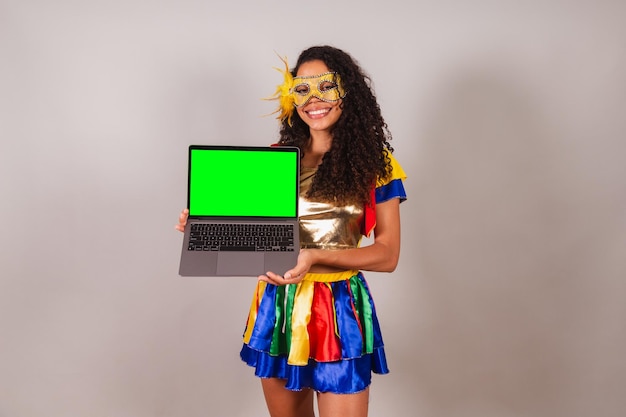 Beautiful black Brazilian woman wearing carnival clothes holding notebook programming web