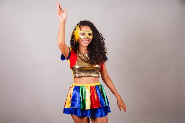 Красивая черная бразильянка в карнавальной одежде frevo в маске танцует самбу