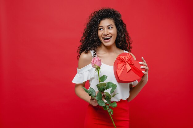 ピンクのバラとハート型のバレンタインギフト赤に分離された美しい黒の女の子