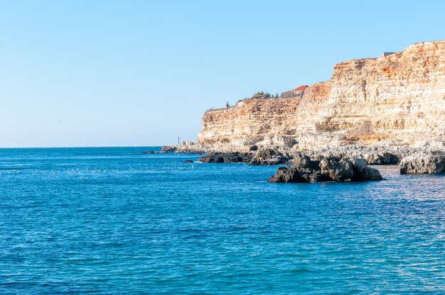 Foto bellissimi paesaggi del mar nero nel sud della russia. montagne arancioni e molti uccelli sulla spiaggia scogli