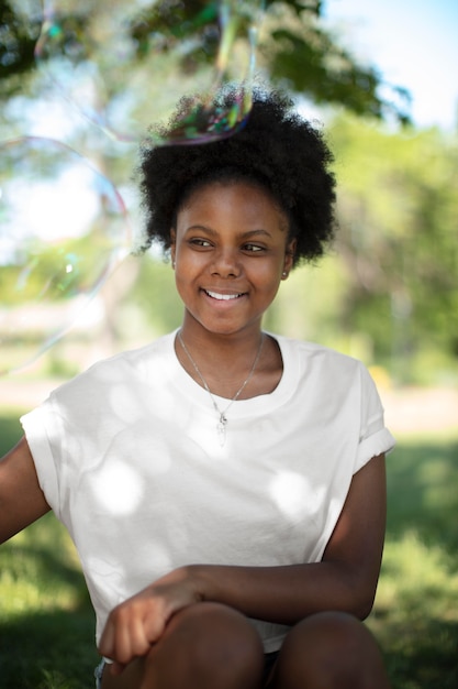 Photo beautiful black teenage girl playing with soap bubbles