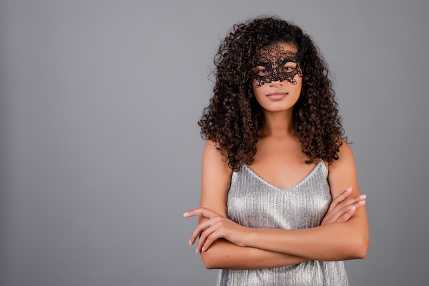 Beautiful black woman wearing elegant masquerade mask isolated over grey