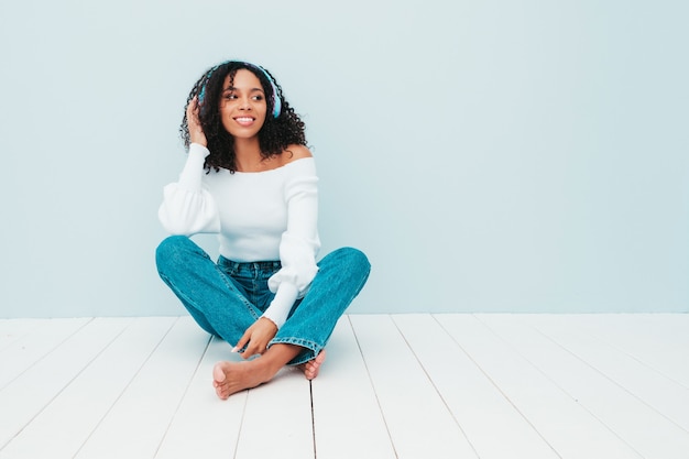 Bella donna di colore con l'acconciatura di riccioli afro. modello sorridente in maglione e jeans