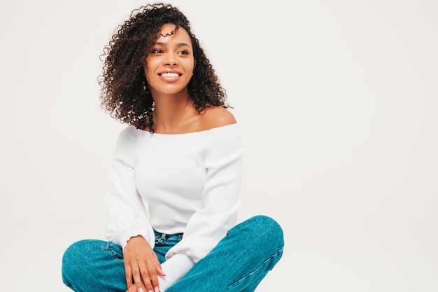 Beautiful black woman with afro curls hairstyle. Smiling model in sweater and trendy jeans clothes