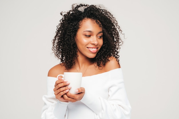 Beautiful black woman with afro curls hairstyle. Smiling model in sweater and trendy jeans clothes.