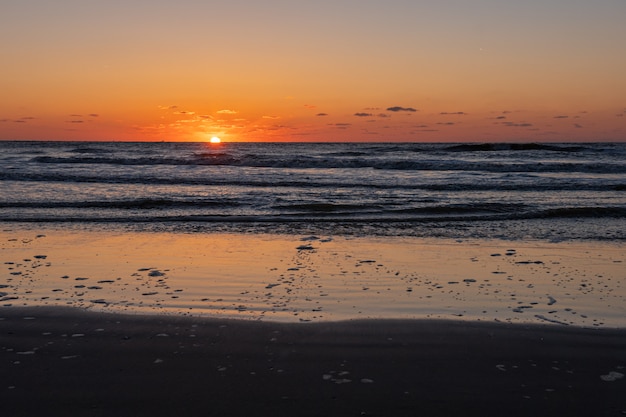 Beautiful blazing sunset landscape at black sea and orange sky above it with awesome sun golden reflection on calm waves as a . Amazing summer sunset view on the beach. Russian nature, Sochi