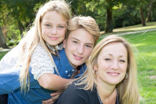 Bella famiglia bionda all'aperto sull'erba nel parco volti sorridenti