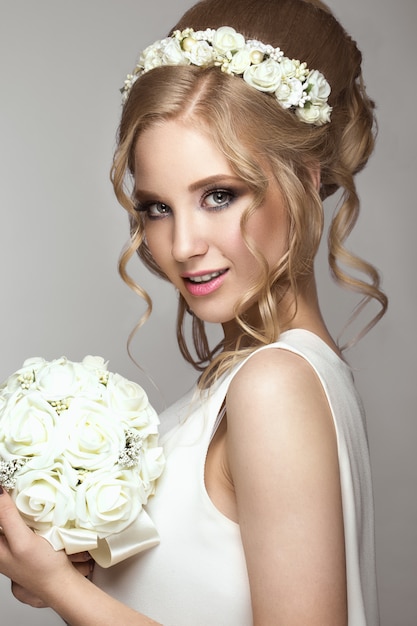 Beautiful blond girl in image of the bride with white flowers on her head