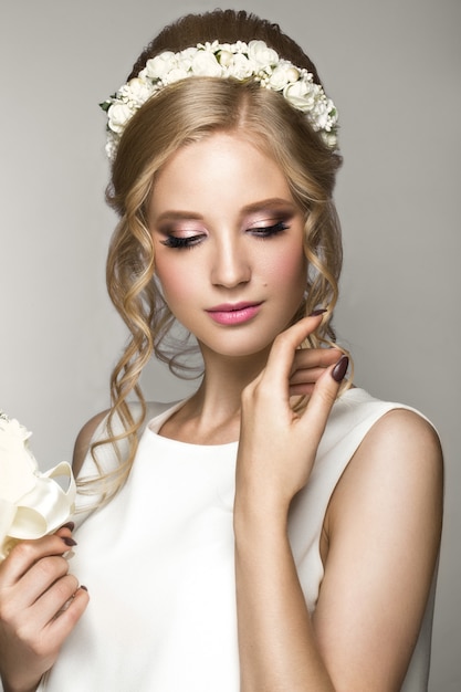 Beautiful blond girl in image of the bride with white flowers on her head