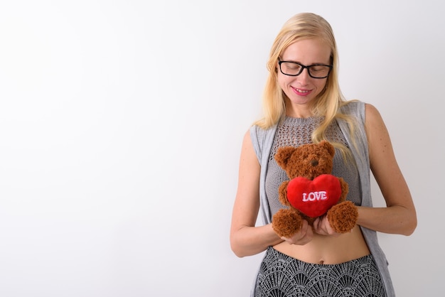 Beautiful blond woman standing against white wall