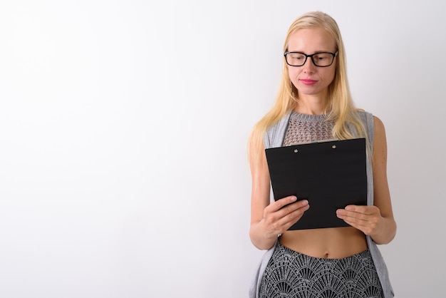 Beautiful blond woman standing against white wall