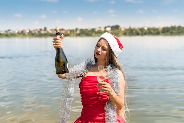 Beautiful blond woman with champagne standing in water