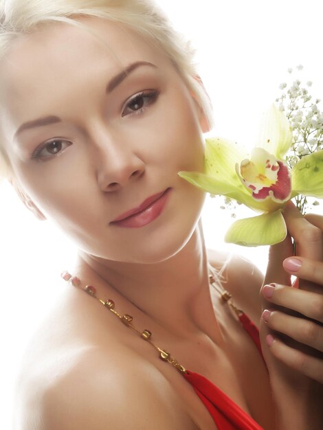 Foto bella donna bionda con il fiore verde dell'orchidea