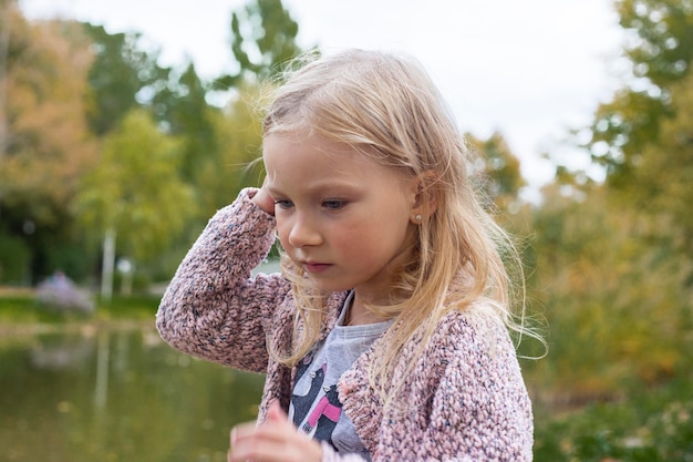 Beautiful blonde baby girl near the lake in the park