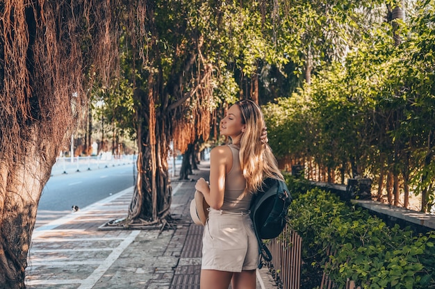 Beautiful blonde backpacker woman walking at the street