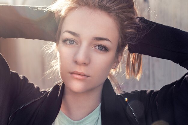 Beautiful blonde in a black cape posing against the background of a concrete wall