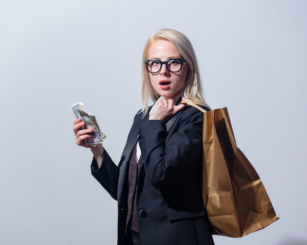 Beautiful blonde businesswoman in suit with shopping bag and money