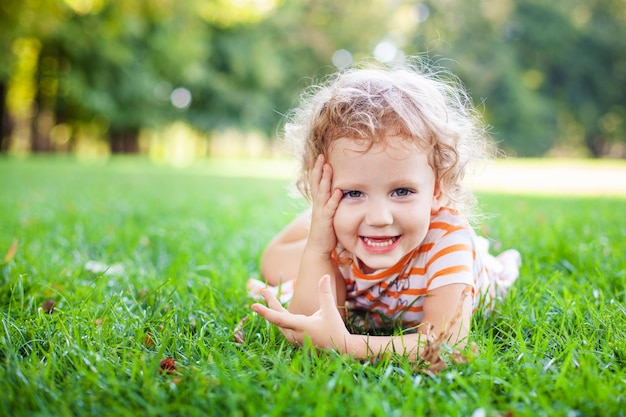 Красивая белокурая девушка керла снаружи в поле с солнечным светом на ее волосах