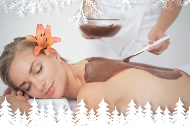 Photo beautiful blonde enjoying a chocolate beauty treatment  against fir tree forest and snowflakes