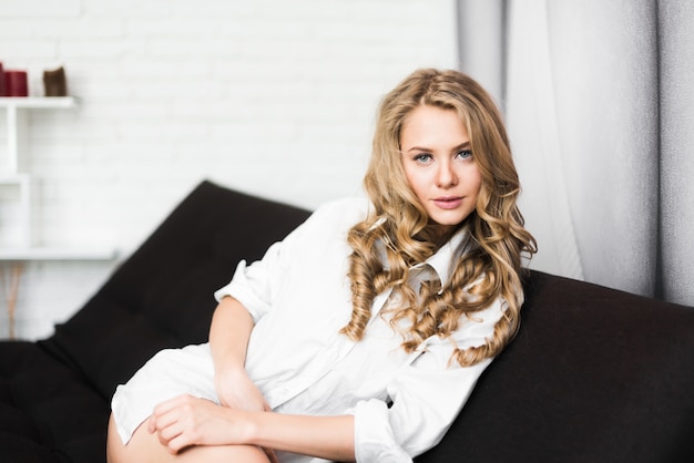 Beautiful blonde girl on a chair in a white shirt